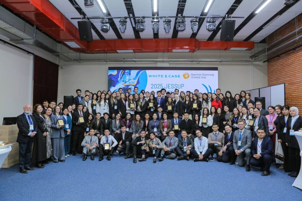 Teams, coaches and judges of the 2025 Central Asian Rounds gathered in the hall in front of the White & Case and American University of Central Asia screen.