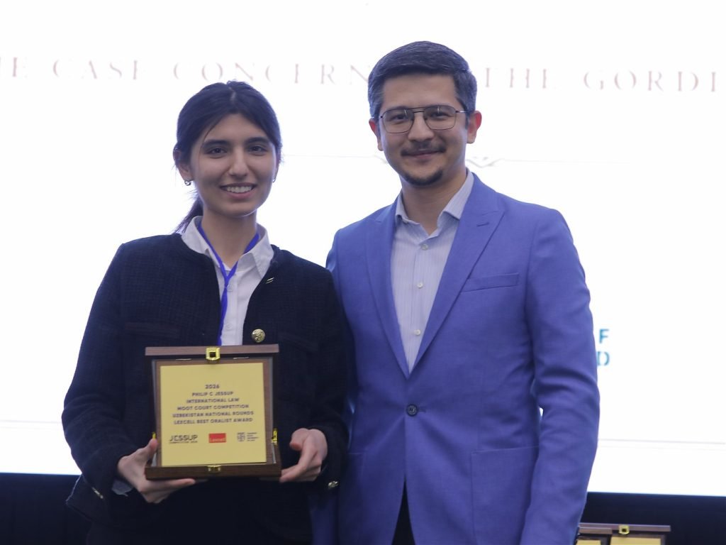 A student receives the Lexcell Best Oralist Award plaque from a sponsor representative at the 2026 Uzbekistan National Rounds.