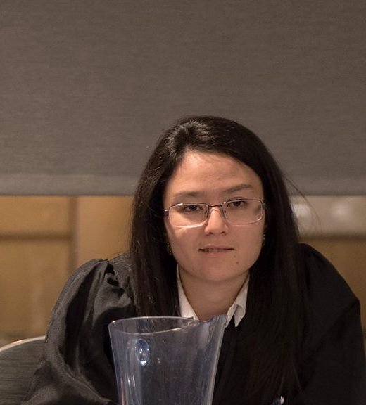A judge in a black robe and glasses sits at the bench during a Jessup round.