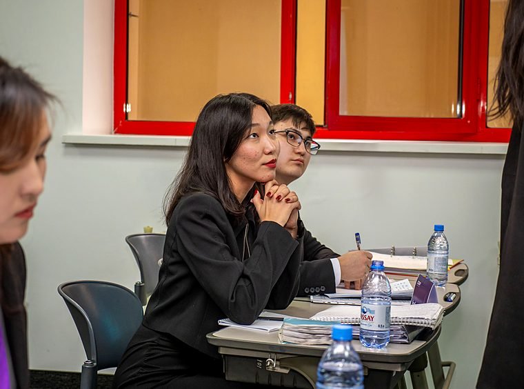 A student with clasped hands and a focused expression listens during a round.